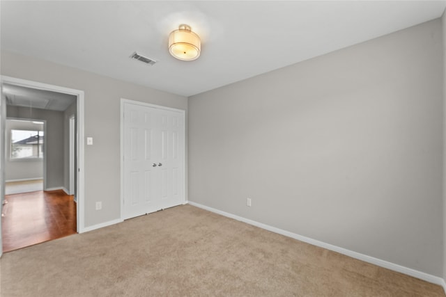 unfurnished bedroom with light colored carpet and a closet