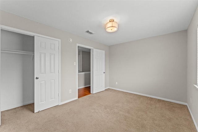 unfurnished bedroom with a closet and light carpet