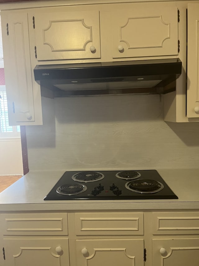 kitchen with black electric cooktop, white cabinetry, and range hood