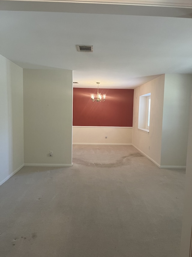 spare room with light carpet and an inviting chandelier