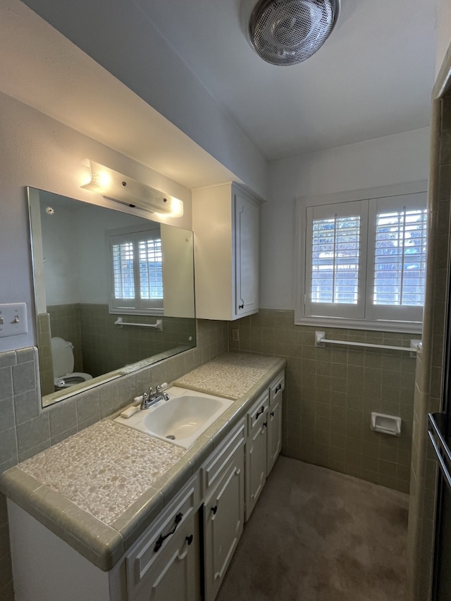 bathroom with tile walls, vanity, and toilet