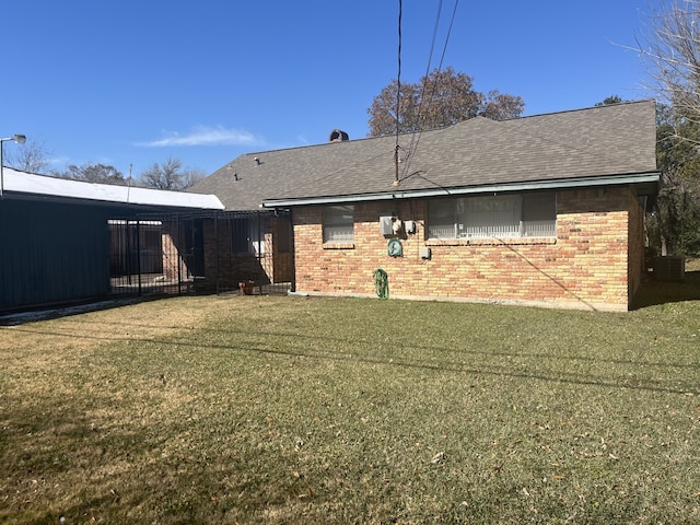 rear view of property featuring central AC and a lawn