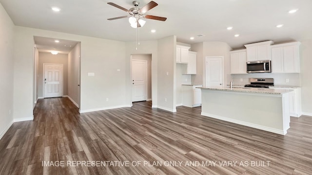 kitchen with white cabinetry, appliances with stainless steel finishes, light stone counters, and a center island with sink