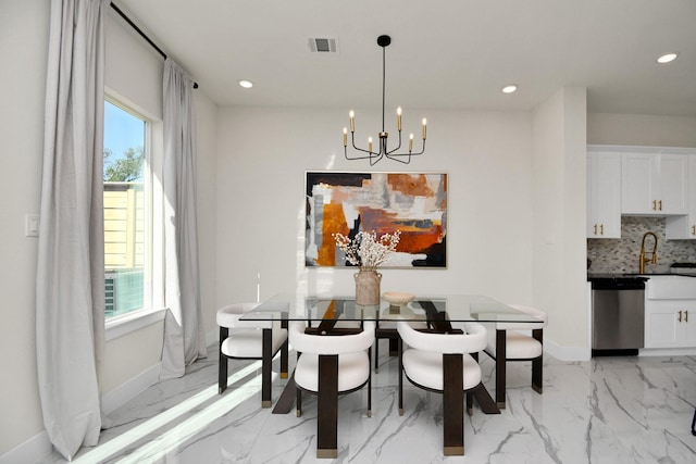 dining space with a healthy amount of sunlight, a chandelier, and sink