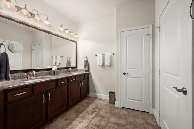 bathroom featuring double vanity, a sink, and baseboards
