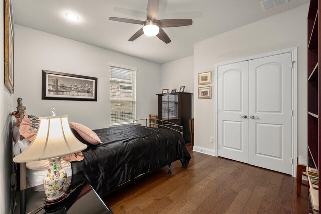 bedroom with ceiling fan, dark wood-style flooring, visible vents, baseboards, and a closet