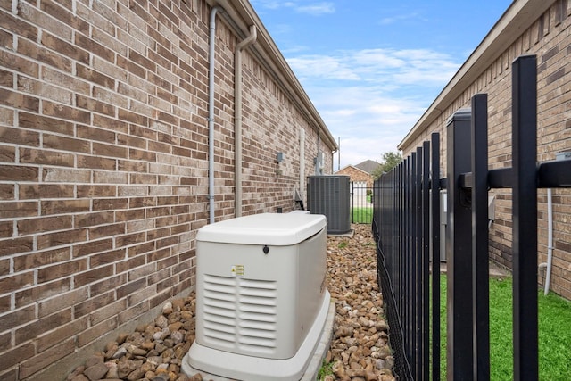 view of side of property featuring brick siding, fence, a gate, and central air condition unit