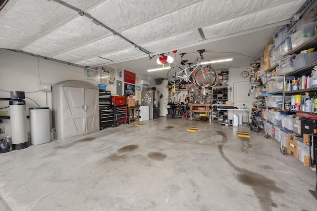 garage featuring a garage door opener, freestanding refrigerator, and a workshop area