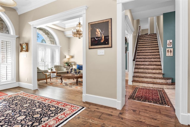 foyer entrance featuring an inviting chandelier, wood-type flooring, crown molding, and a raised ceiling