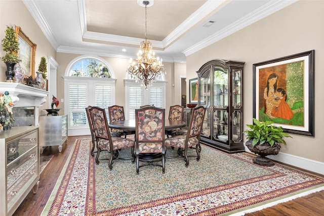 dining space with a raised ceiling, ornamental molding, dark hardwood / wood-style floors, and a notable chandelier