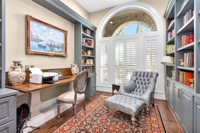 home office featuring a wealth of natural light, dark wood-type flooring, and built in desk