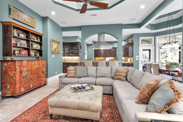 tiled living room featuring a raised ceiling and ceiling fan