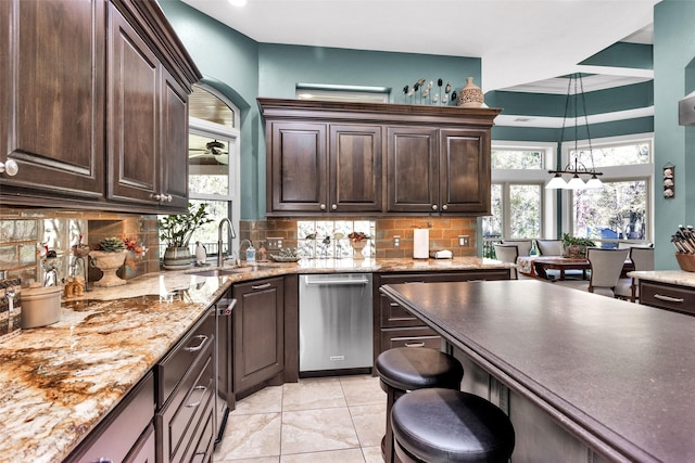 kitchen featuring decorative light fixtures, sink, decorative backsplash, stainless steel dishwasher, and dark brown cabinetry