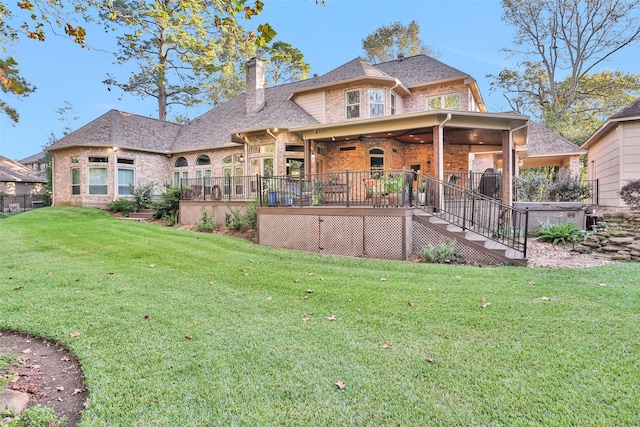 back of property featuring a hot tub, ceiling fan, and a lawn