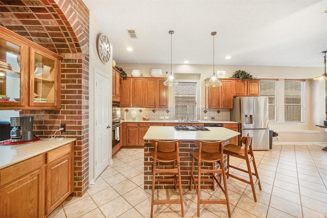 kitchen featuring light tile patterned floors, stainless steel appliances, a kitchen breakfast bar, and a kitchen island