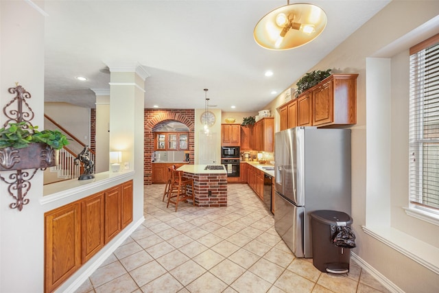 kitchen featuring hanging light fixtures, a center island, a wealth of natural light, black appliances, and ornate columns