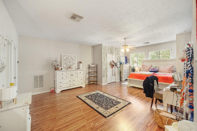 bedroom featuring ceiling fan, light hardwood / wood-style floors, and a textured ceiling