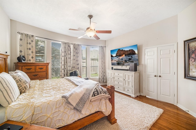 bedroom featuring wood-type flooring, a textured ceiling, ceiling fan, and a closet