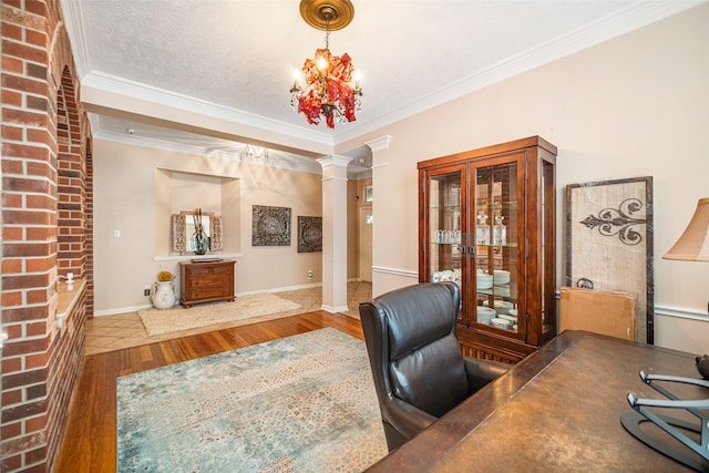 office featuring an inviting chandelier, ornamental molding, hardwood / wood-style floors, and ornate columns