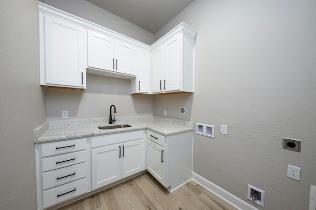 clothes washing area with sink, electric dryer hookup, cabinets, washer hookup, and light hardwood / wood-style floors