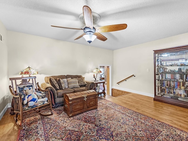 living room featuring hardwood / wood-style flooring, ceiling fan, and a textured ceiling