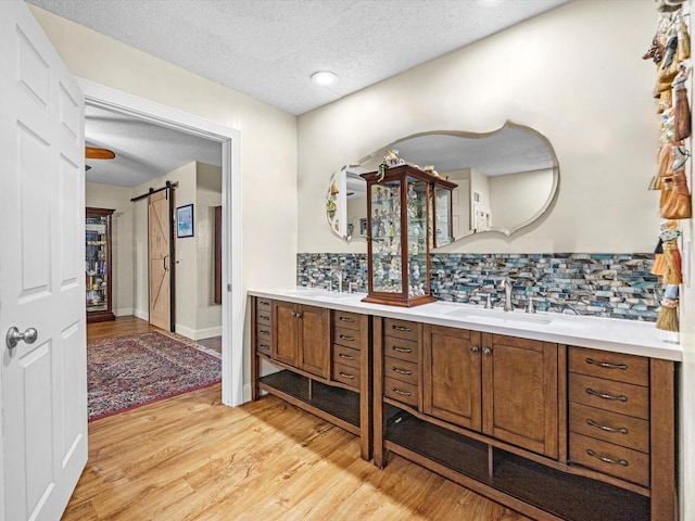 bathroom featuring vanity, hardwood / wood-style floors, a textured ceiling, and backsplash