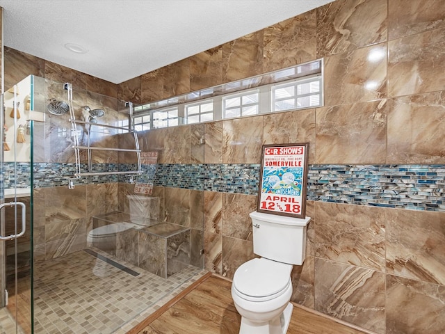 bathroom featuring a textured ceiling, a shower with door, and toilet