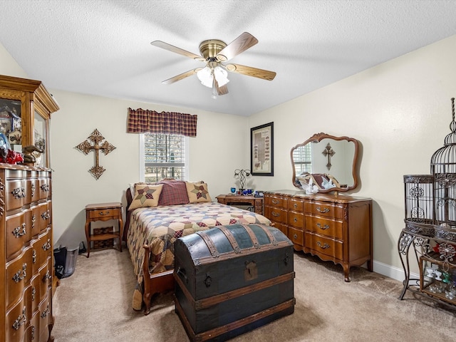 bedroom with ceiling fan, light colored carpet, and a textured ceiling