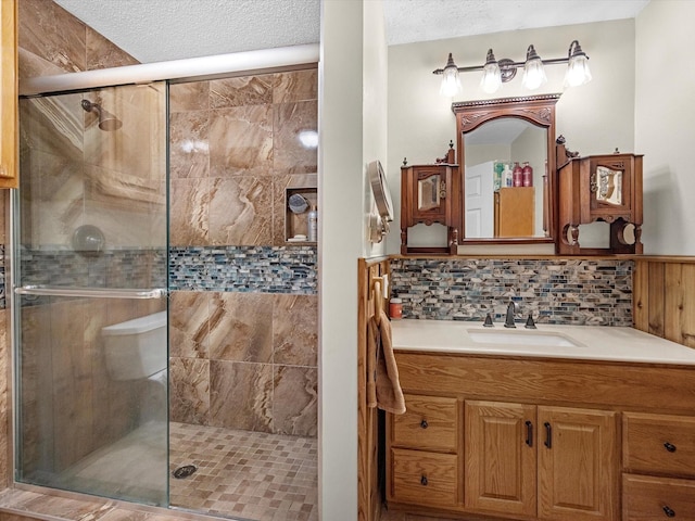 bathroom featuring tasteful backsplash, vanity, an enclosed shower, and a textured ceiling