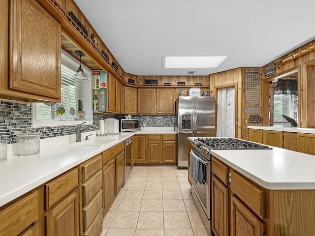 kitchen with decorative light fixtures, sink, backsplash, light tile patterned floors, and stainless steel appliances