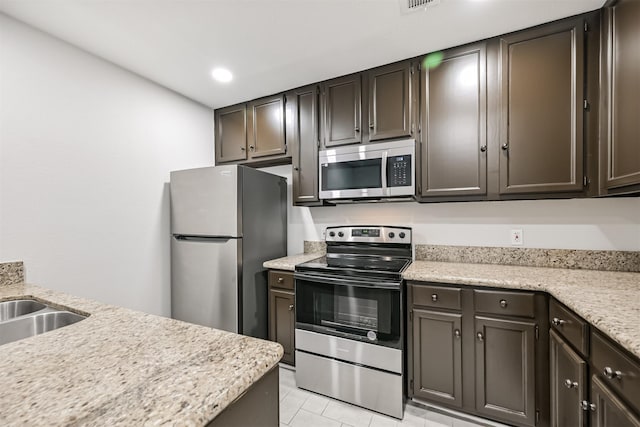 kitchen featuring stainless steel appliances, sink, dark brown cabinets, and light tile patterned floors