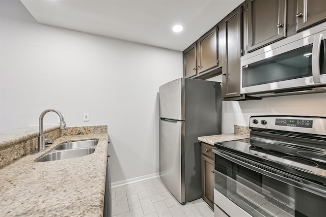 kitchen featuring light stone counters, appliances with stainless steel finishes, sink, and dark brown cabinets