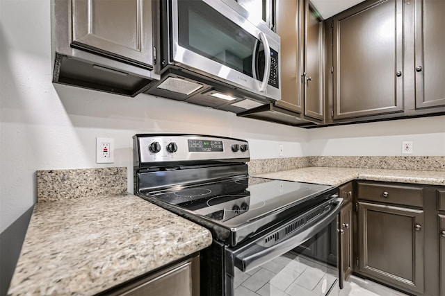 kitchen with light stone counters, stainless steel appliances, and dark brown cabinets