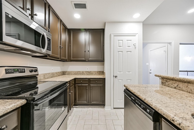 kitchen featuring dark brown cabinetry, appliances with stainless steel finishes, and light stone countertops