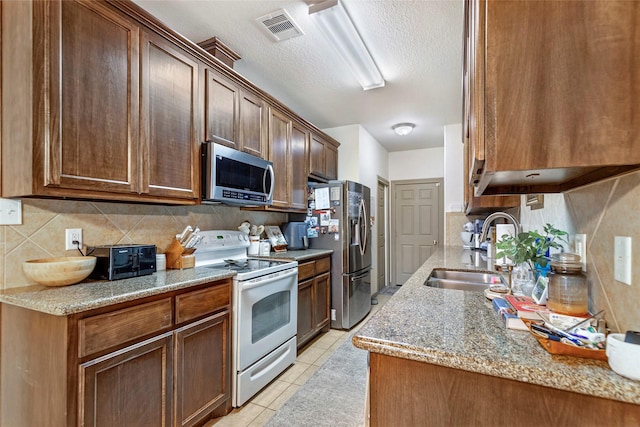 kitchen with tasteful backsplash, sink, light tile patterned floors, and stainless steel appliances