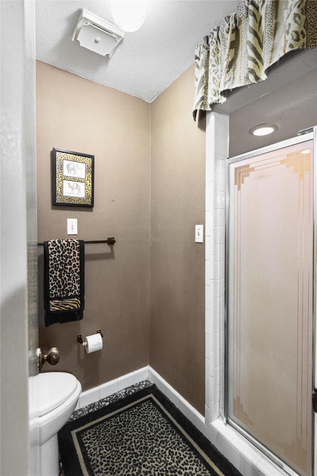 bathroom featuring toilet and a shower with shower door