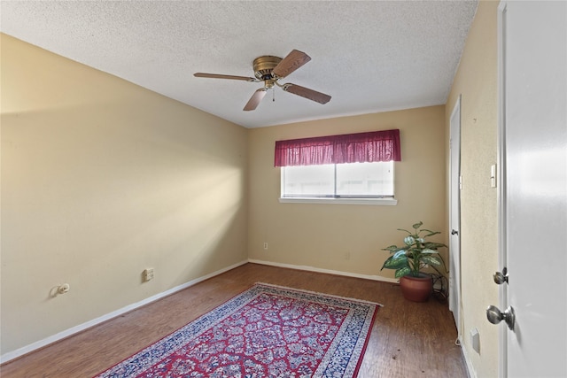 spare room featuring wood-type flooring, ceiling fan, and a textured ceiling