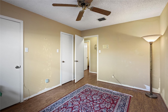 bedroom featuring ceiling fan, dark hardwood / wood-style flooring, and a textured ceiling