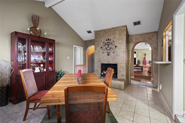 tiled dining space featuring lofted ceiling with beams and a large fireplace