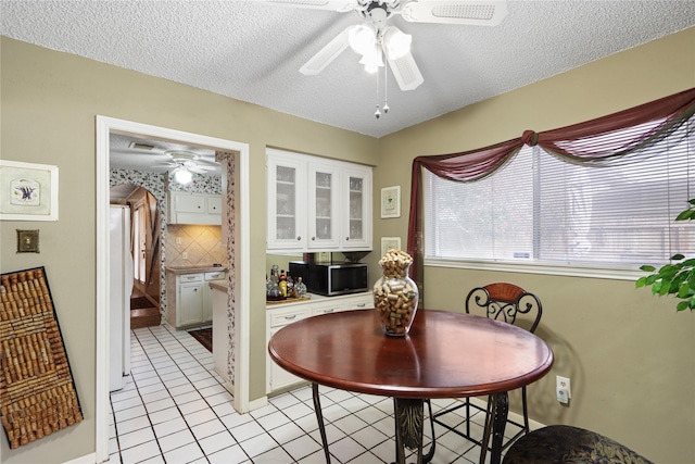 dining space with ceiling fan, a textured ceiling, and light tile patterned floors