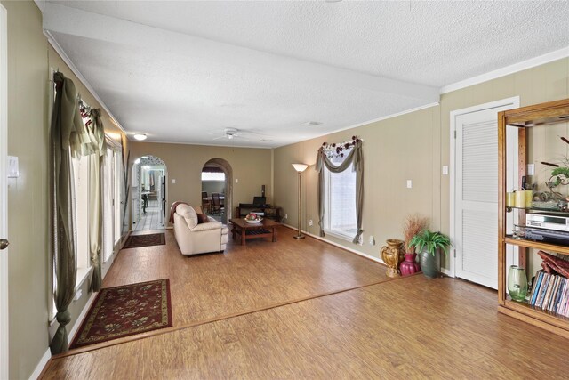 unfurnished living room with crown molding, ceiling fan, hardwood / wood-style floors, and a textured ceiling