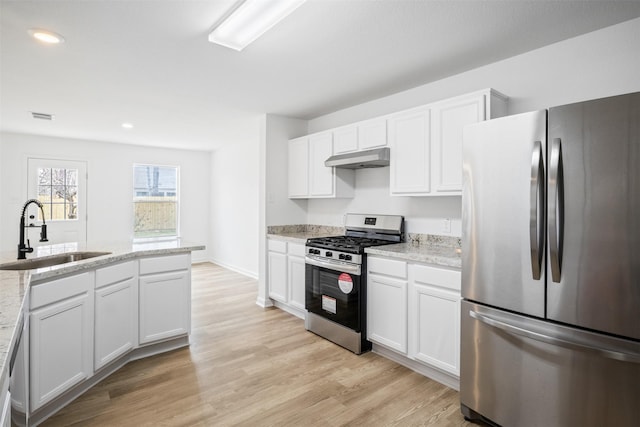 kitchen with sink, appliances with stainless steel finishes, white cabinetry, light stone countertops, and light hardwood / wood-style floors