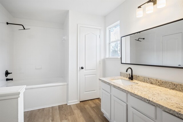 bathroom with washtub / shower combination, wood-type flooring, and vanity