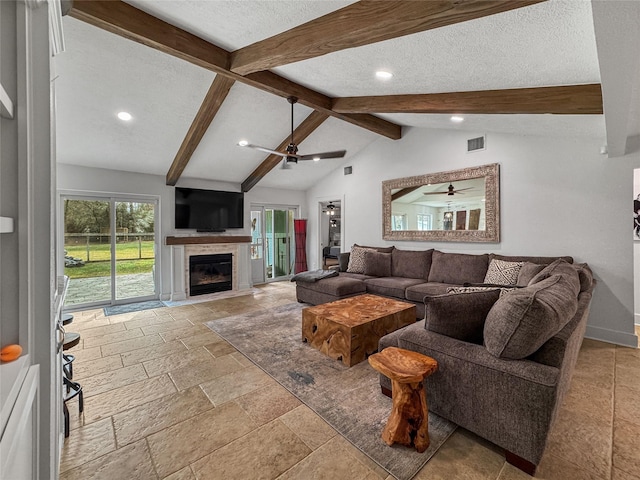 living room with visible vents, lofted ceiling with beams, a fireplace with flush hearth, stone tile flooring, and a textured ceiling