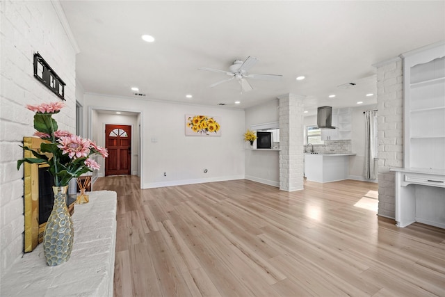 living room featuring ceiling fan, brick wall, light hardwood / wood-style flooring, and ornamental molding