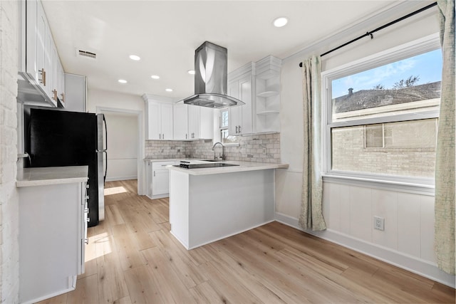 kitchen featuring stainless steel fridge, light hardwood / wood-style flooring, white cabinetry, island range hood, and kitchen peninsula