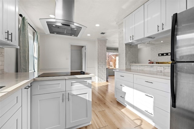 kitchen featuring island range hood, stainless steel refrigerator, white cabinetry, backsplash, and light hardwood / wood-style flooring