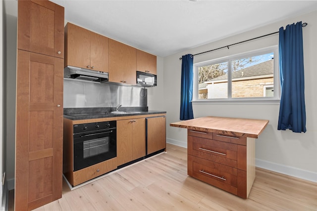 kitchen with sink, light hardwood / wood-style flooring, butcher block countertops, and black appliances