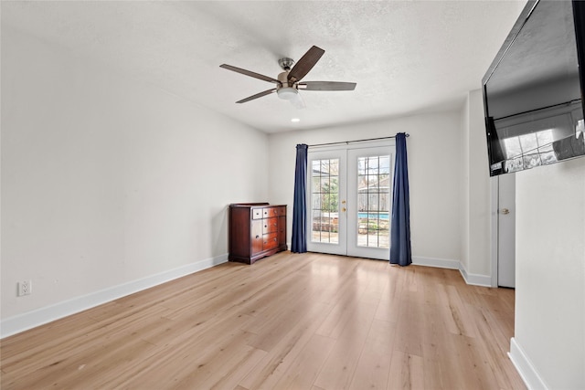 empty room featuring ceiling fan, light hardwood / wood-style flooring, french doors, and a textured ceiling