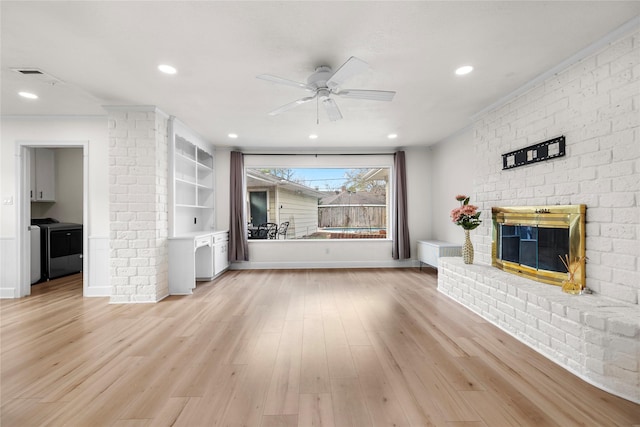 unfurnished living room with ceiling fan, a fireplace, independent washer and dryer, and light hardwood / wood-style flooring